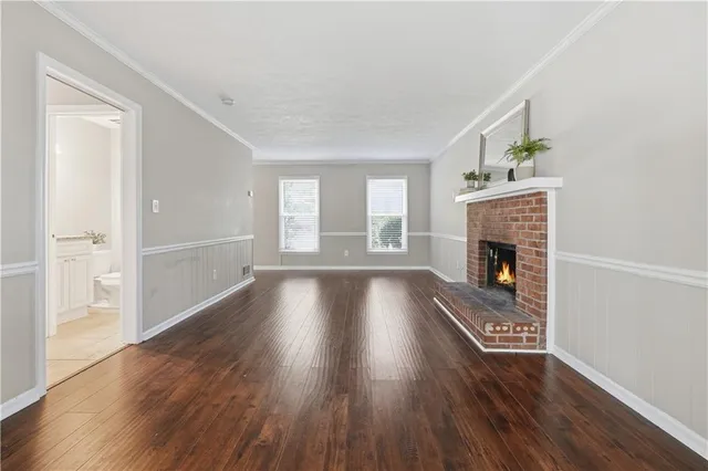 an empty room with wooden floor a fireplace and windows