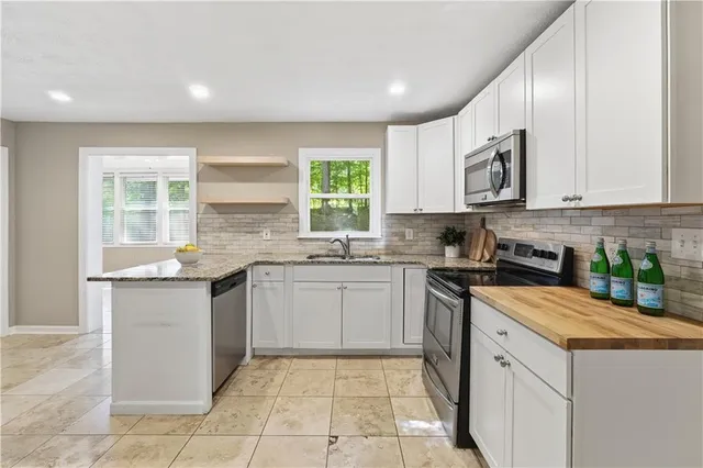 a kitchen with stainless steel appliances granite countertop a stove a sink and a microwave