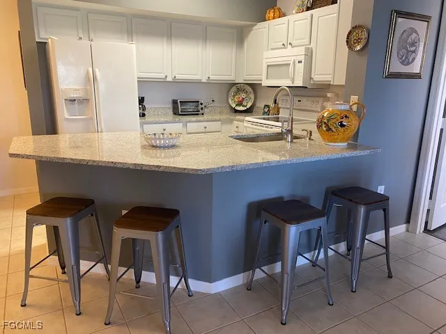 a kitchen with stainless steel appliances granite countertop a table chairs sink and cabinets