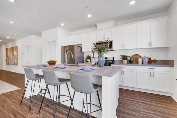 a kitchen with stainless steel appliances a white table chairs and a refrigerator