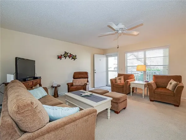 a living room with furniture ceiling fan and a window