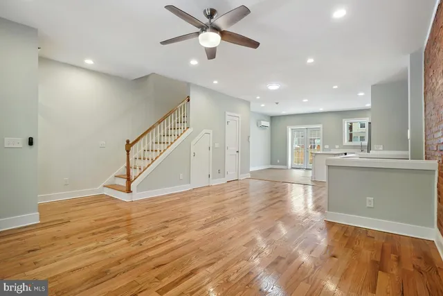 a view of an empty room with wooden floor and a ceiling fan