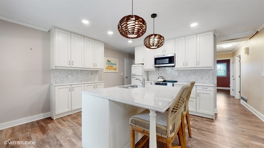 2321 Spring Hill Lane Lindenhurst, IL 60046 - Photo 8 of 30 a kitchen with a table chairs and a clock on the wall