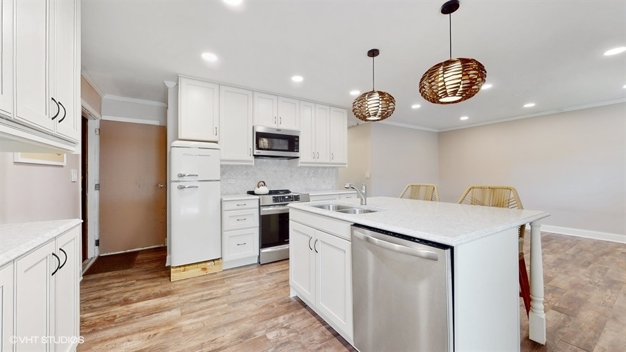 2321 Spring Hill Lane Lindenhurst, IL 60046 - Photo 9 of 30 a kitchen with a refrigerator a stove top oven a kitchen island a stove and a refrigerator with wooden floor