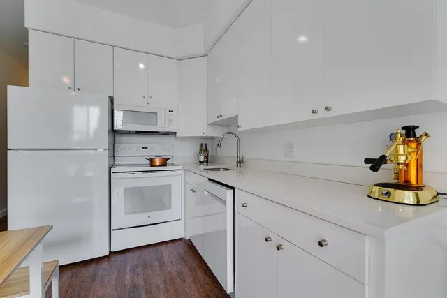 a kitchen with a refrigerator and white cabinets