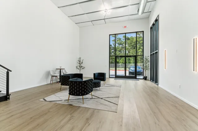 a living room with furniture large window and wooden floor