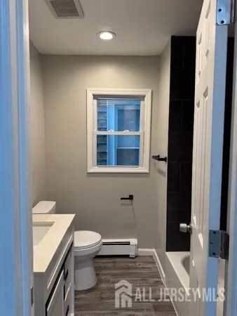 a bathroom with a granite countertop toilet and a sink