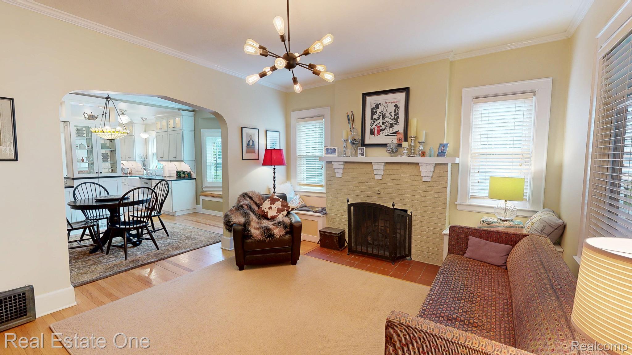 410 West 4th Street Rochester, MI 48307 - Photo 7 of 33 Living area featuring a prominent fireplace with a detailed mantel, wood-finish flooring, and an arched doorway leading to a dining space