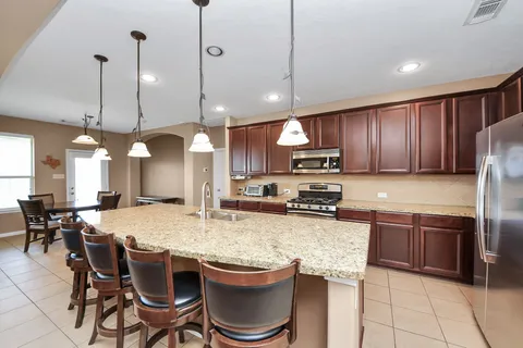 a kitchen with granite countertop kitchen island stainless steel appliances a stove a sink a dining table and chairs