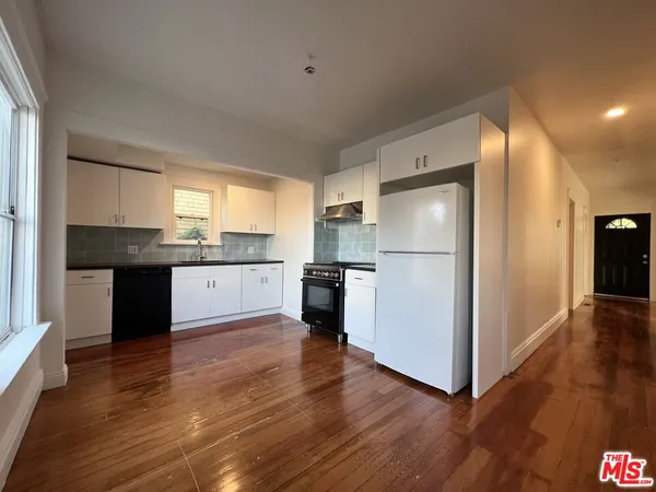 a kitchen with wooden floors and white appliances
