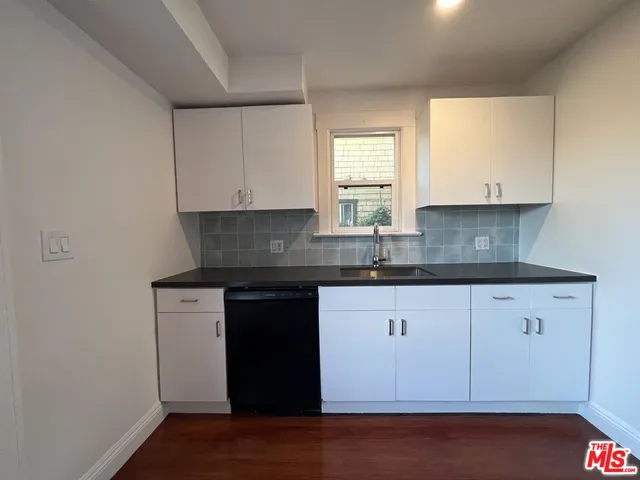 a kitchen with granite countertop white cabinets sink and window