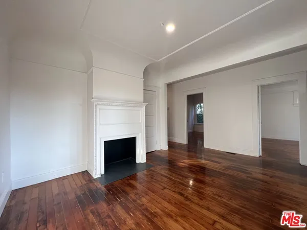 a view of empty room with wooden floor and fireplace