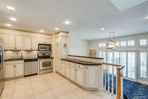 a kitchen with stainless steel appliances granite countertop a stove top oven a sink dishwasher and a refrigerator