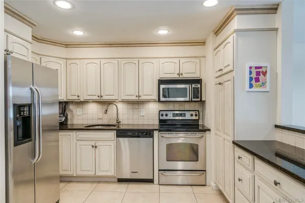 a kitchen with granite countertop white cabinets and stainless steel appliances