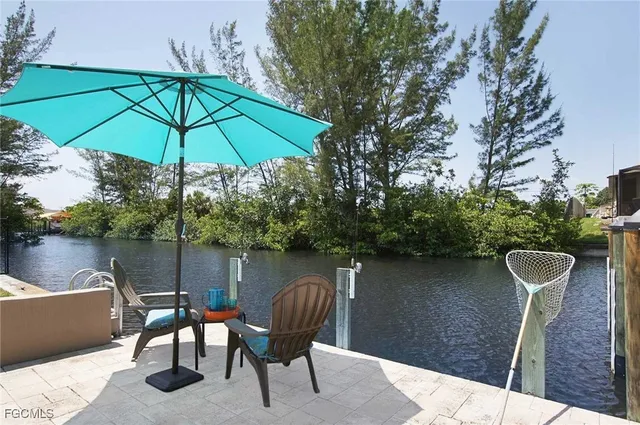 a view of a patio with table and chairs potted plants and large tree