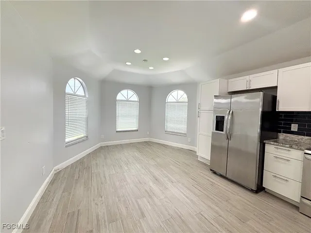 a view of a kitchen with wooden floor electronic appliances and windows