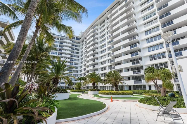 a view of a tall building with a yard and palm trees