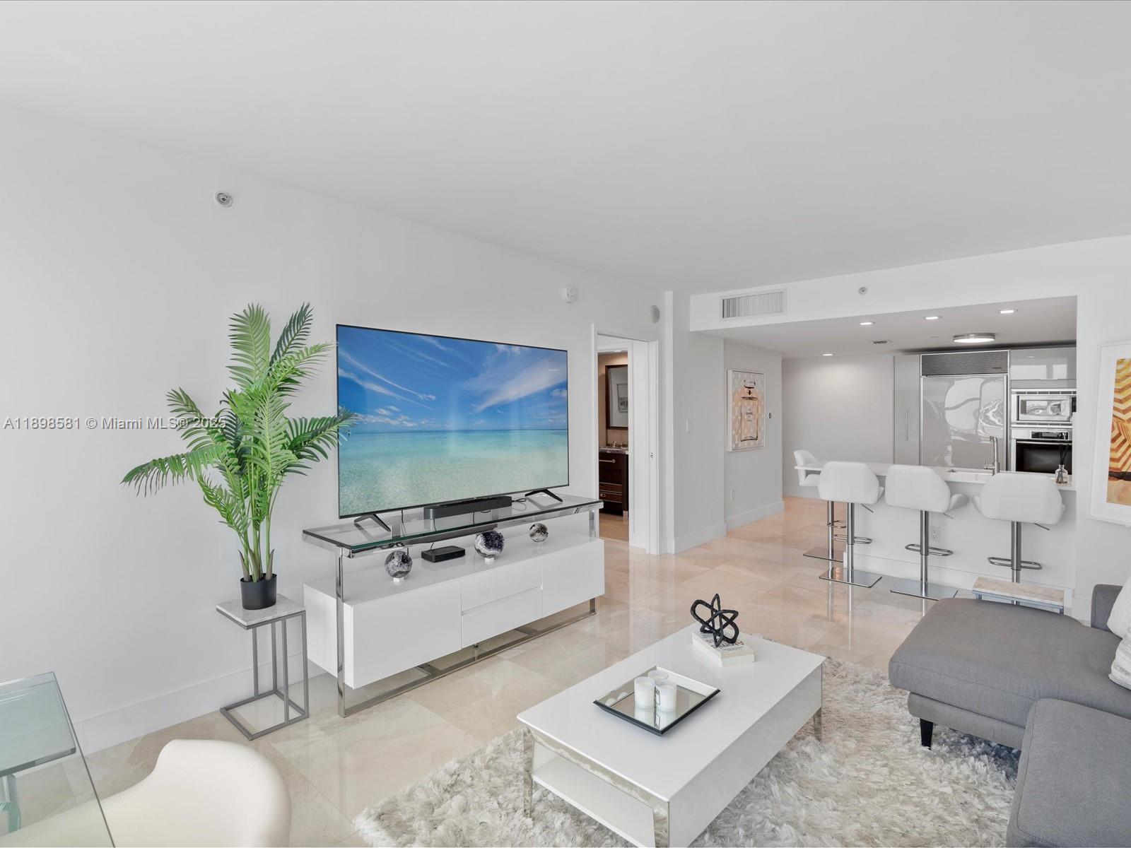 6801 Collins Avenue, Unit 1402 Miami Beach, FL 33141 - Photo 11 of 50 a living room with furniture a flat screen tv and a potted plant