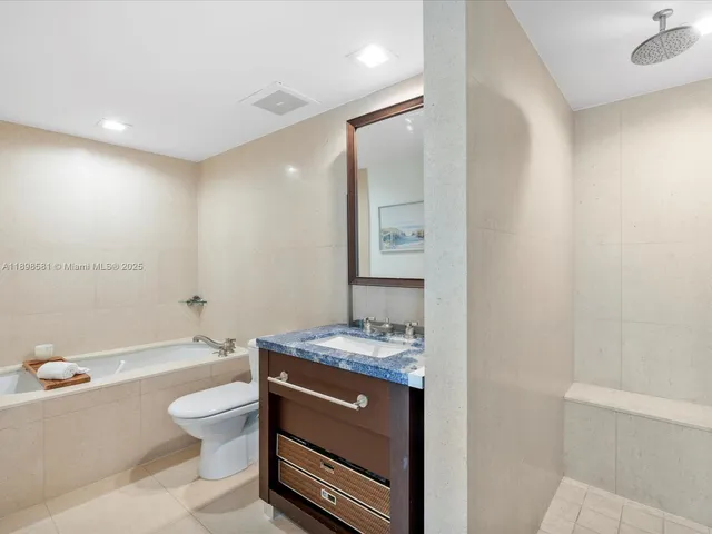 a bathroom with a granite countertop sink mirror vanity and toilet
