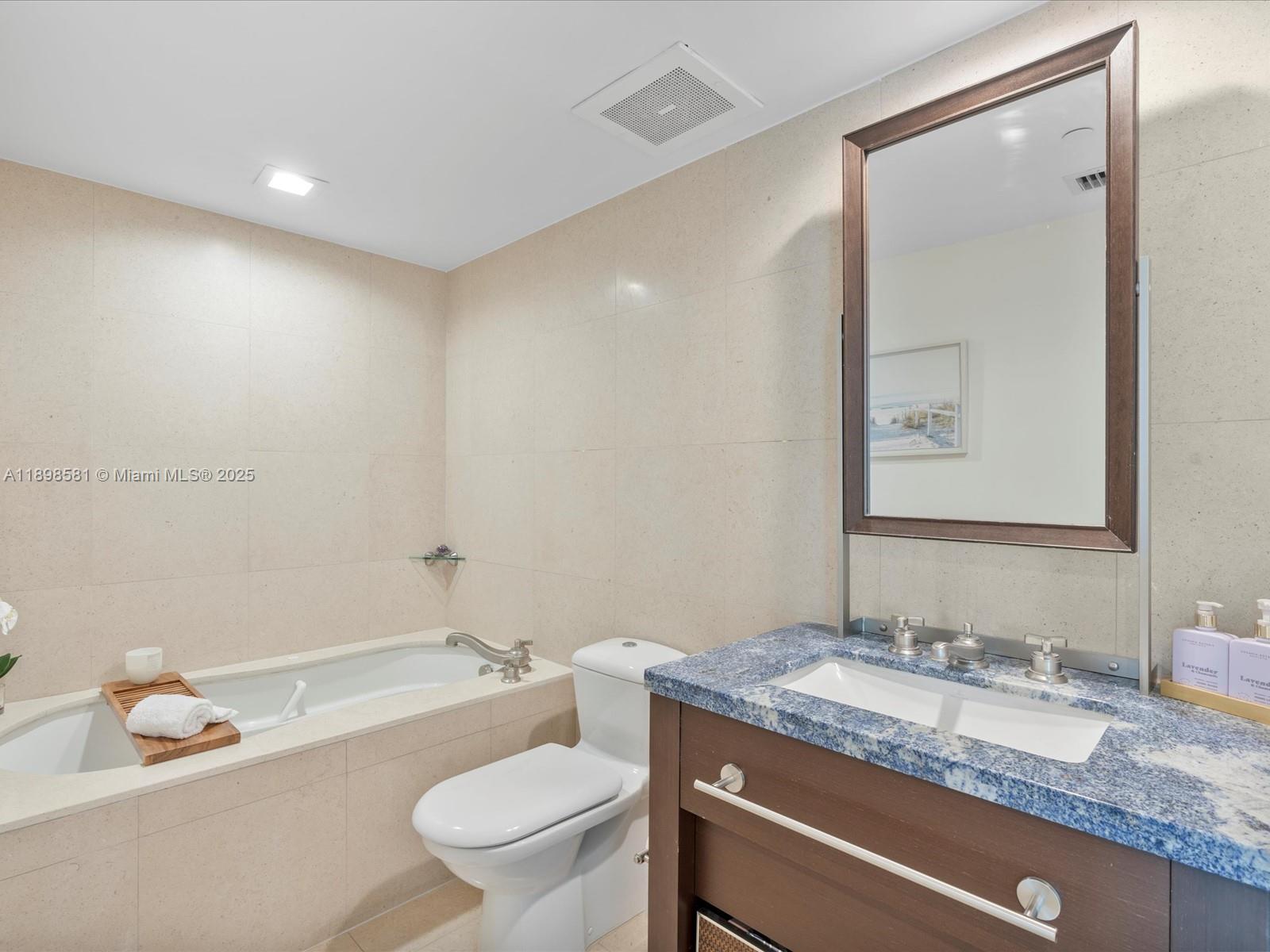 6801 Collins Avenue, Unit 1402 Miami Beach, FL 33141 - Photo 35 of 50 a bathroom with a granite countertop sink mirror vanity and toilet