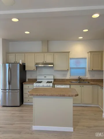 a kitchen with stainless steel appliances granite countertop a refrigerator a stove and a sink