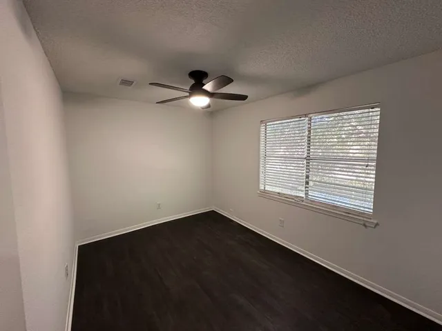 an empty room with a window and a fan
