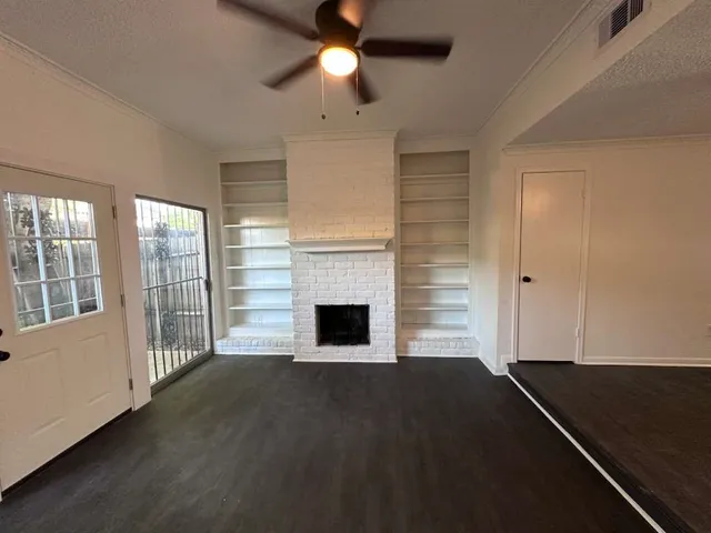 an empty room with wooden floor fireplace and windows