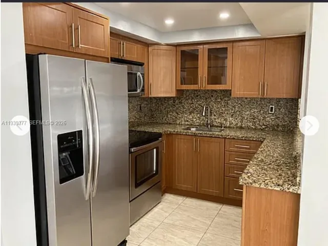 a kitchen with granite countertop a refrigerator and a sink