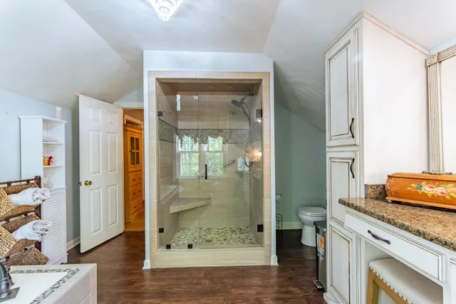 a bathroom with a granite countertop sink a mirror and a shower