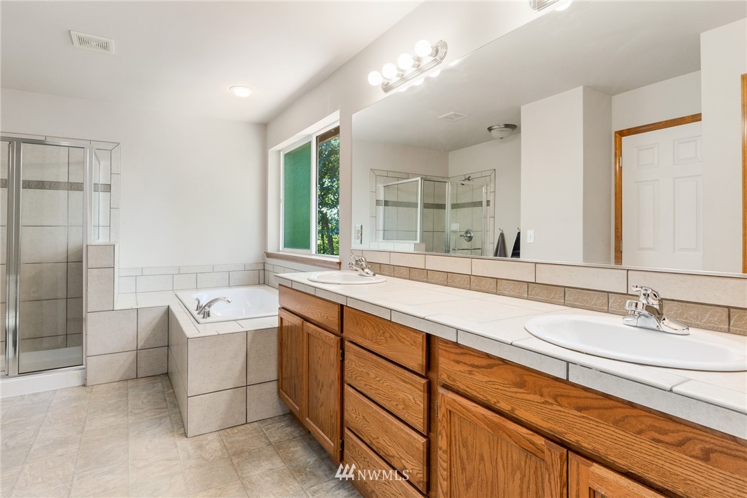 16008 Sunset Road Bothell, WA 98012 - Photo 16 of 28 a spacious bathroom with a granite countertop sink a toilet a mirror and shower