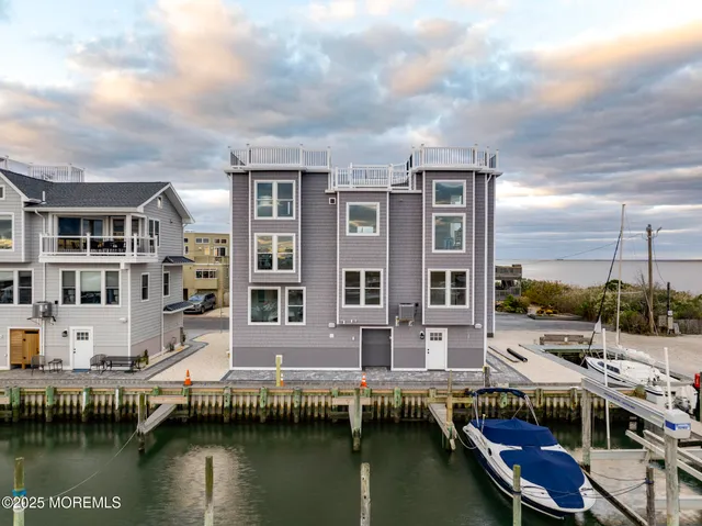 a large living room with wooden floors and kitchen view
