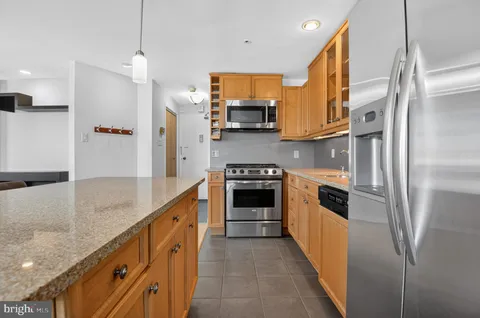 a kitchen with stainless steel appliances granite countertop a refrigerator a stove and a sink