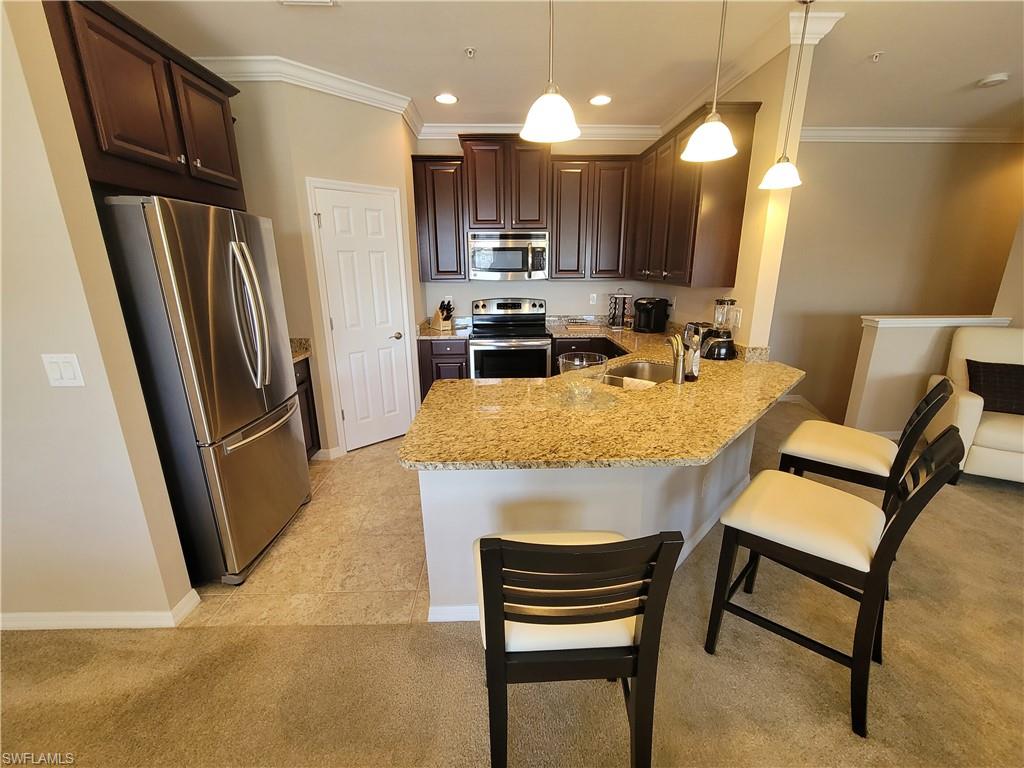 8561 Violeta Street, Unit 202 Estero, FL 34135 - Photo 12 of 40 a kitchen with refrigerator a sink and chairs