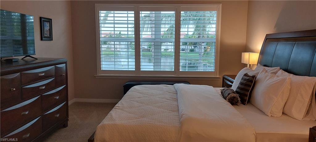 8561 Violeta Street, Unit 202 Estero, FL 34135 - Photo 16 of 40 a bedroom with a bed and a flat tv screen on dresser