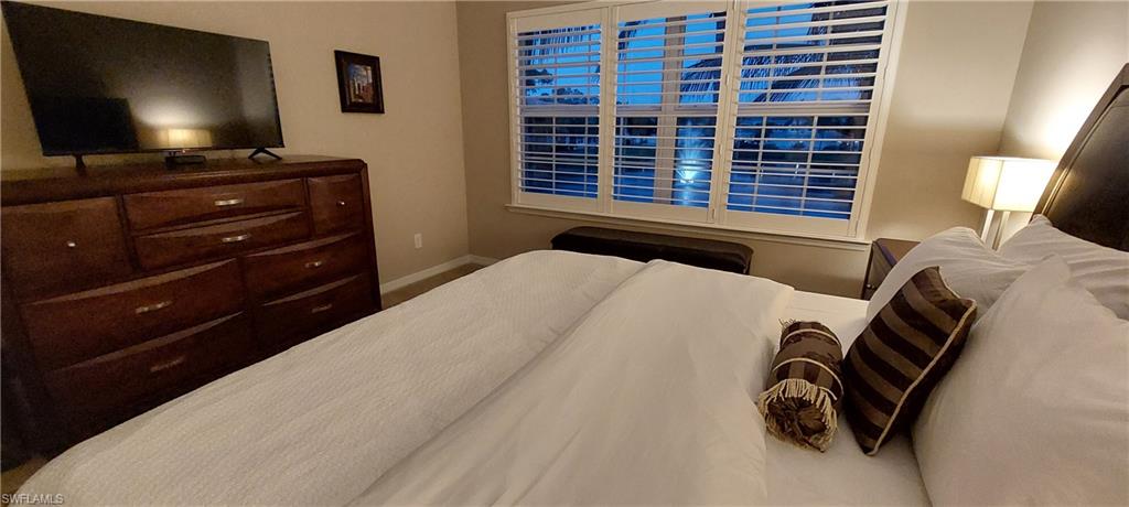 8561 Violeta Street, Unit 202 Estero, FL 34135 - Photo 17 of 40 a bedroom with a bed and a flat screen tv