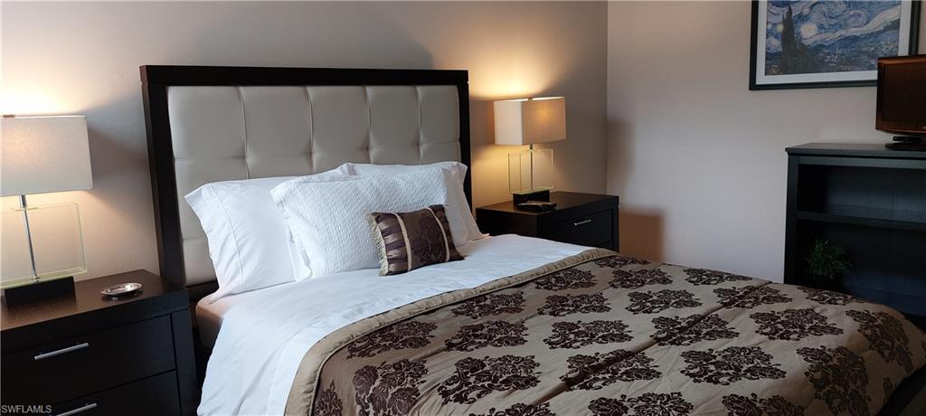 8561 Violeta Street, Unit 202 Estero, FL 34135 - Photo 24 of 40 a bedroom with a bed and a lamp on dresser
