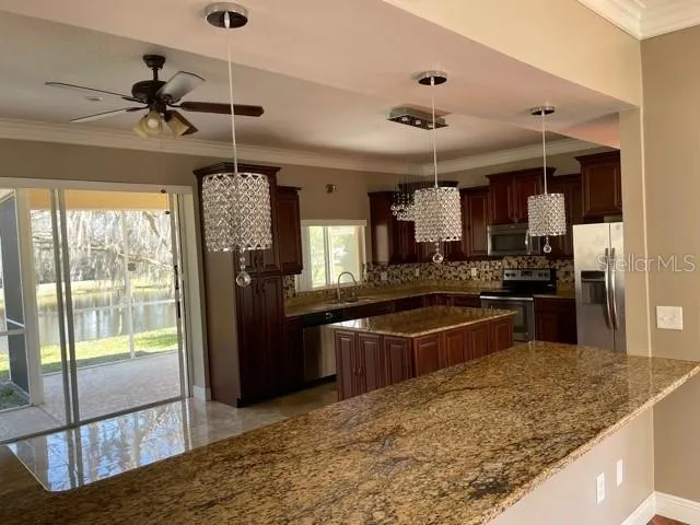 a large kitchen with kitchen island a large counter space appliances and a ceiling fan