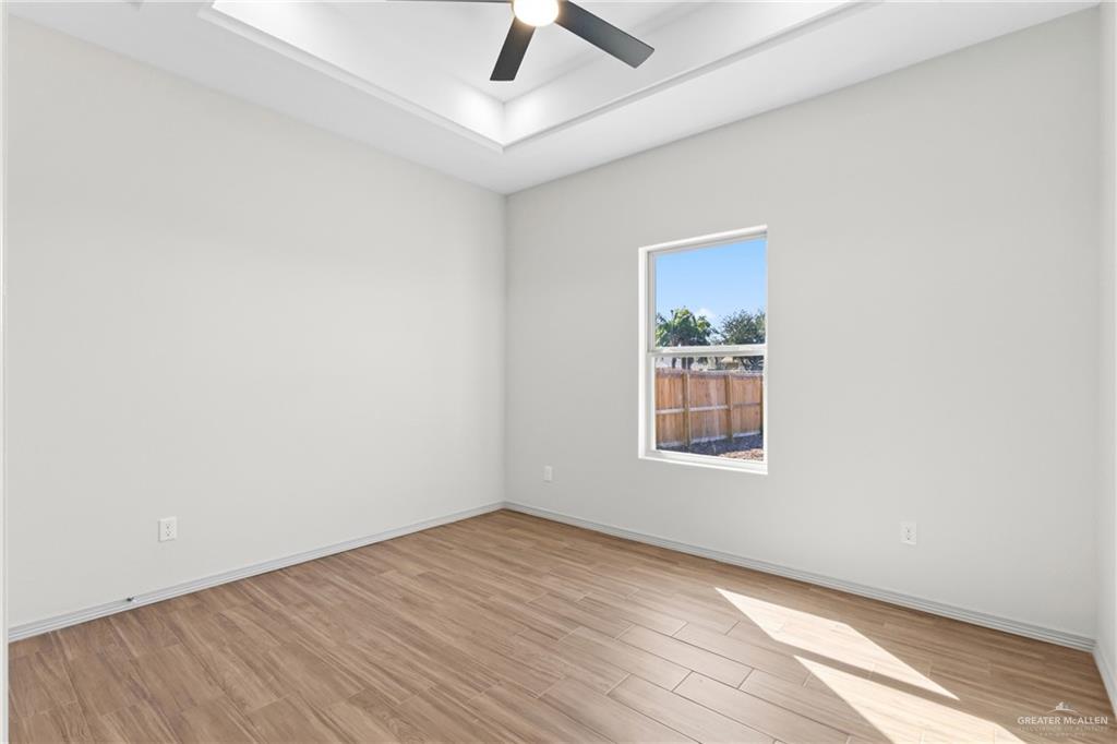 2102 Trinity Street Donna, TX 78537 - Photo 13 of 24 an empty room with wooden floor chandelier fan and windows