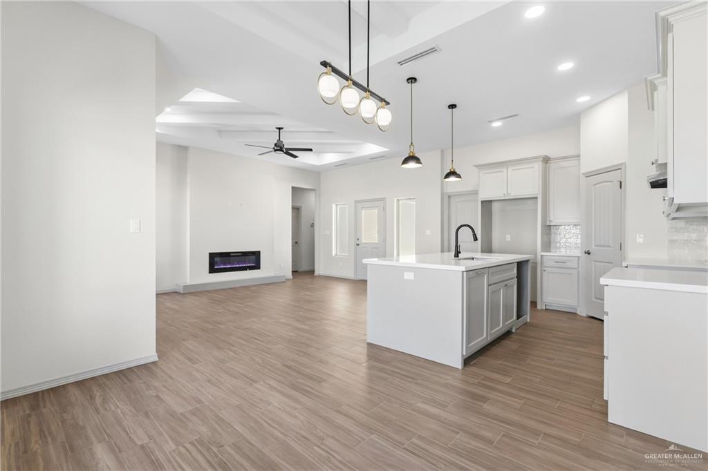 2102 Trinity Street Donna, TX 78537 - Photo 8 of 24 a large kitchen with white cabinets and wooden floor
