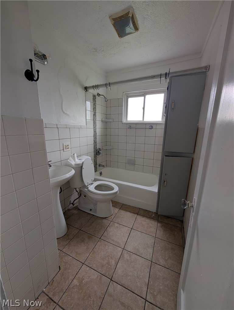 475 East 146th Street Cleveland, OH 44110 - Photo 14 of 28 Bathroom featuring a pedestal sink, white tile walls, a standard bathtub with shower, a window, and a built-in storage cabinet