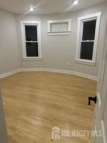 a view of an empty room with wooden floor and cabinet