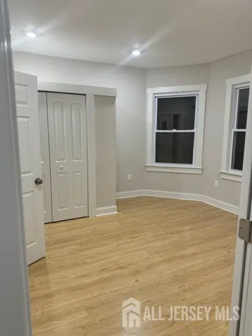 a view of an empty room with wooden floor and windows