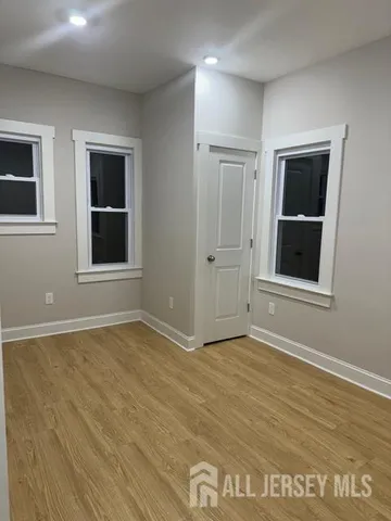 a view of an empty room with wooden floor and windows