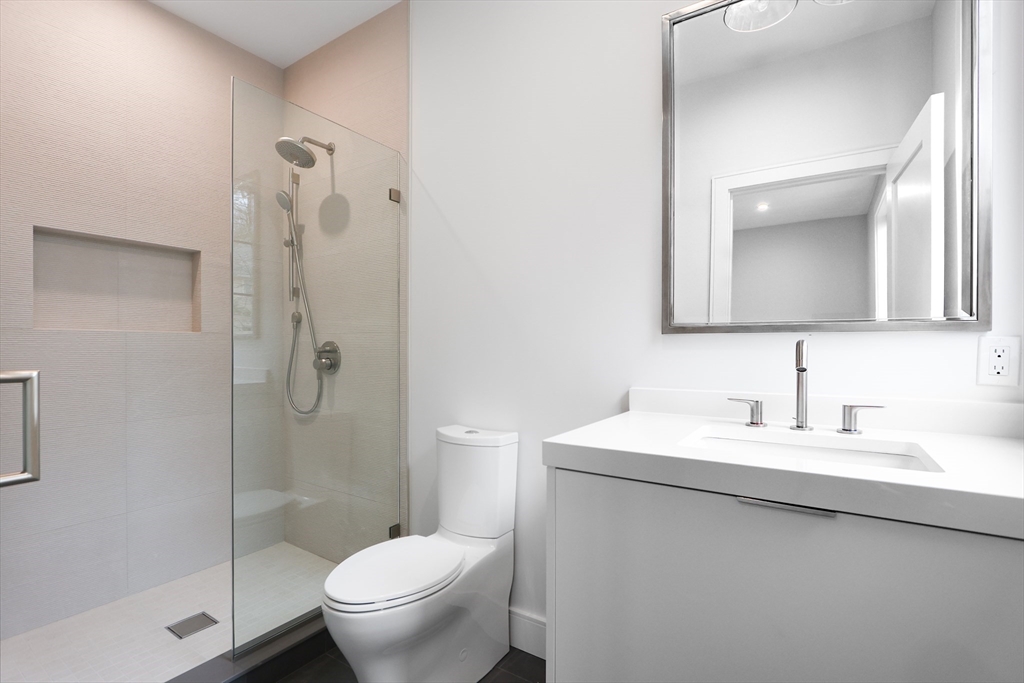 189 Hartman Road Newton, MA 02459 - Photo 18 of 38 a bathroom with a toilet a sink a glass door a shower and a mirror
