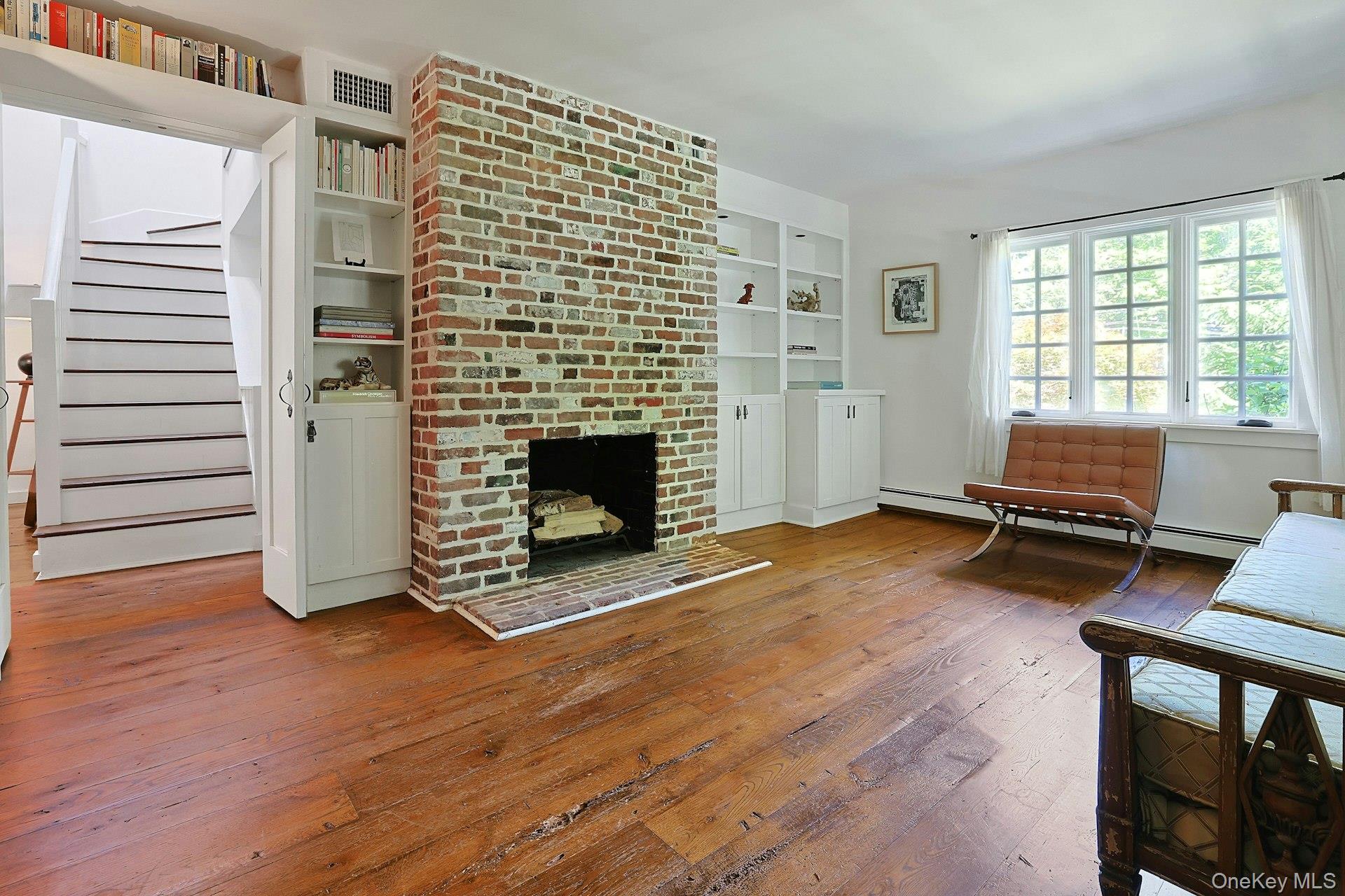 65 Douglas Road Chappaqua, NY 10514 - Photo 6 of 41 A warm and inviting living room centered around a beautiful brick fireplace, creating the perfect setting for cozy evenings, quiet mornings, and effortless gatherings.