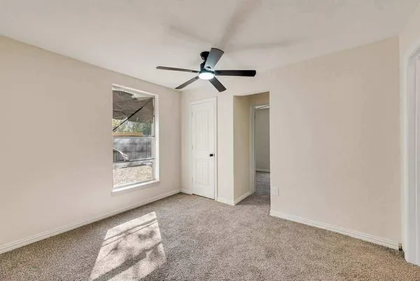 an empty room with windows and fan