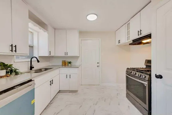 a kitchen with granite countertop a sink a stove and cabinets