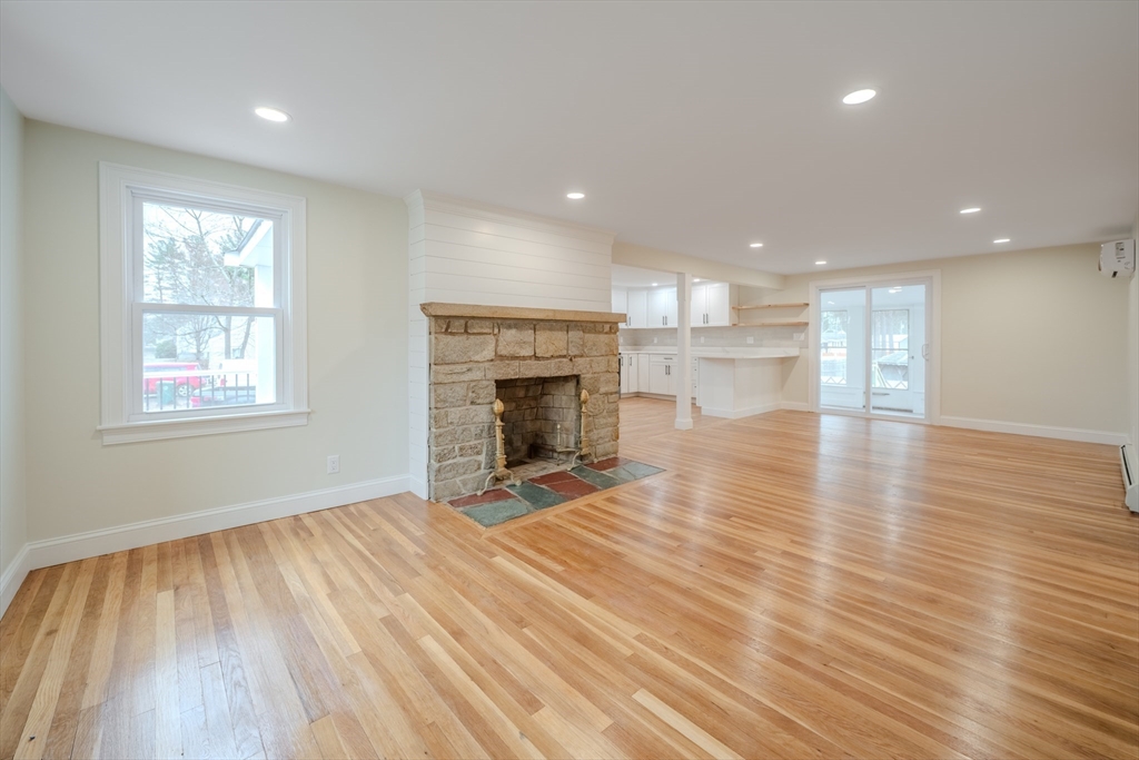 52 Bridge Street Billerica, MA 01821 - Photo 10 of 41 an empty room with wooden floor fireplace and windows