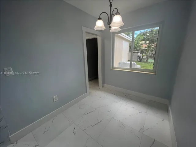 en empty room with window chandelier fan and windows