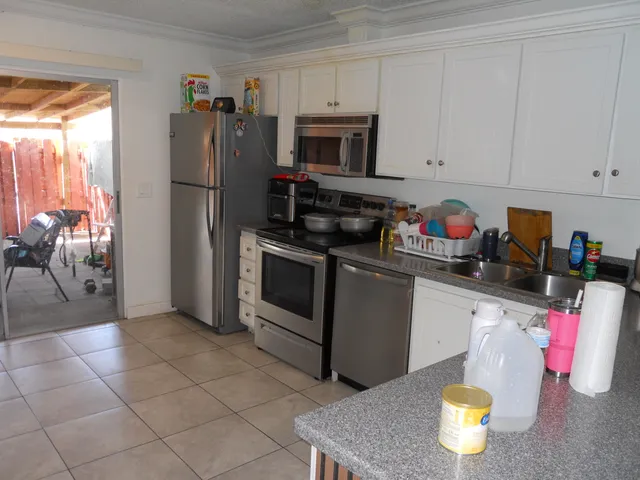 a kitchen with granite countertop a refrigerator and a stove top oven